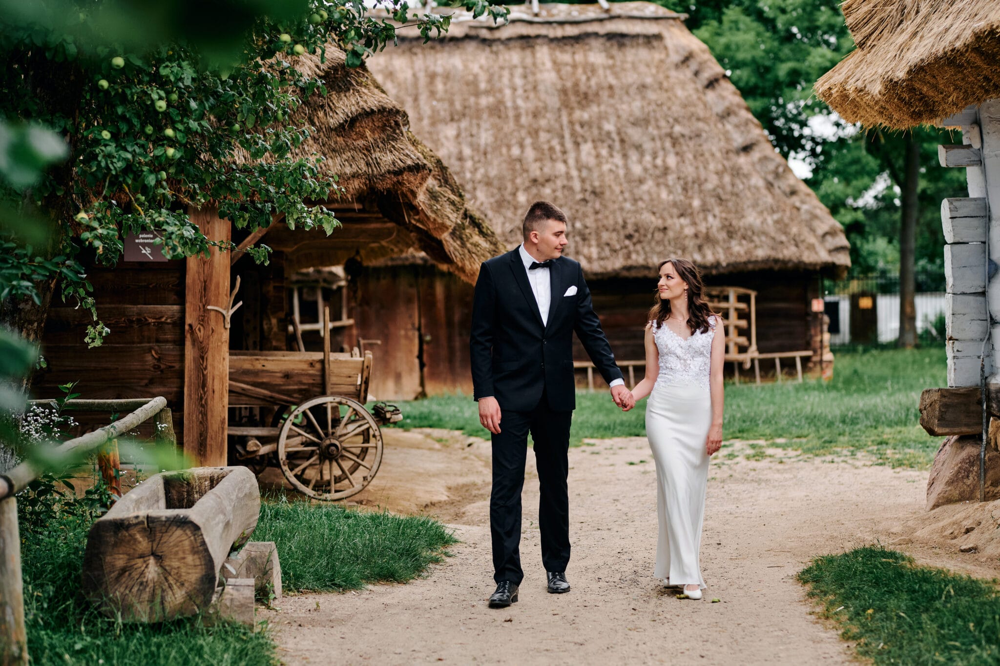 Agata i Radek na tle bujnej zieleni, spleceni w romantycznym objęciu. Idealne ujęcie podkreślające harmonię między parą a naturą. Słowa kluczowe: sesja ślubna w plenerze, romantyczne zdjęcia ślubne, zielona sceneria ślubna.